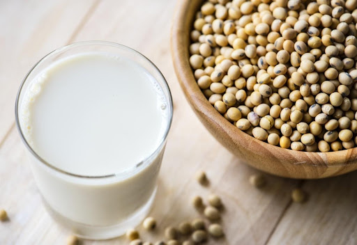 soy in a bowl and glass of soy milk on a brown wood